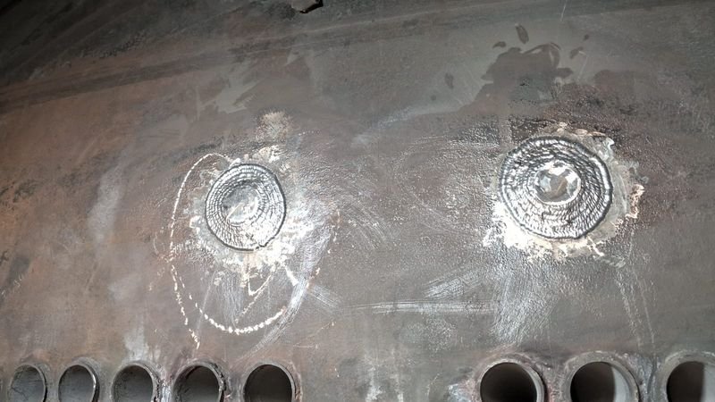Soldas de reparo na chapa de uma caldeira, junto à fileira de tubos
